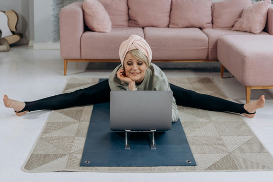 A woman stretching, facing a laptop.